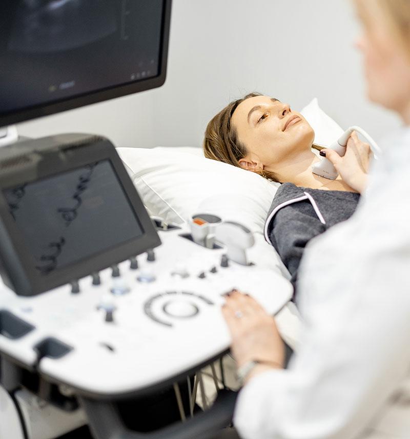 Woman laying down for ultrasound scan on throat